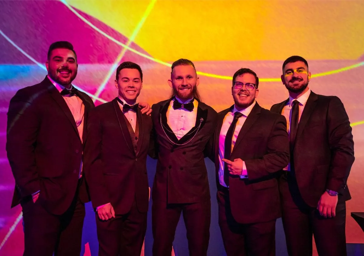 Five guests in black tie posing in front of the projected backdrop at Bad After Dark in Las Vegas