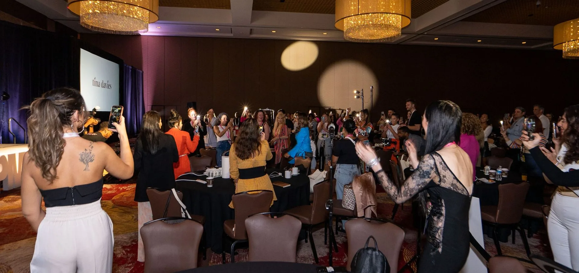 Attendees filming the stage from the floor at PMU World 2023, the Seminole Hard Rock Hotel & Casino in Hollywood, Florida