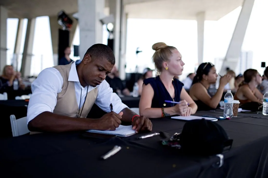 Attendees taking notes at their tables during a session at Scaling With Systems LIVE in Miami